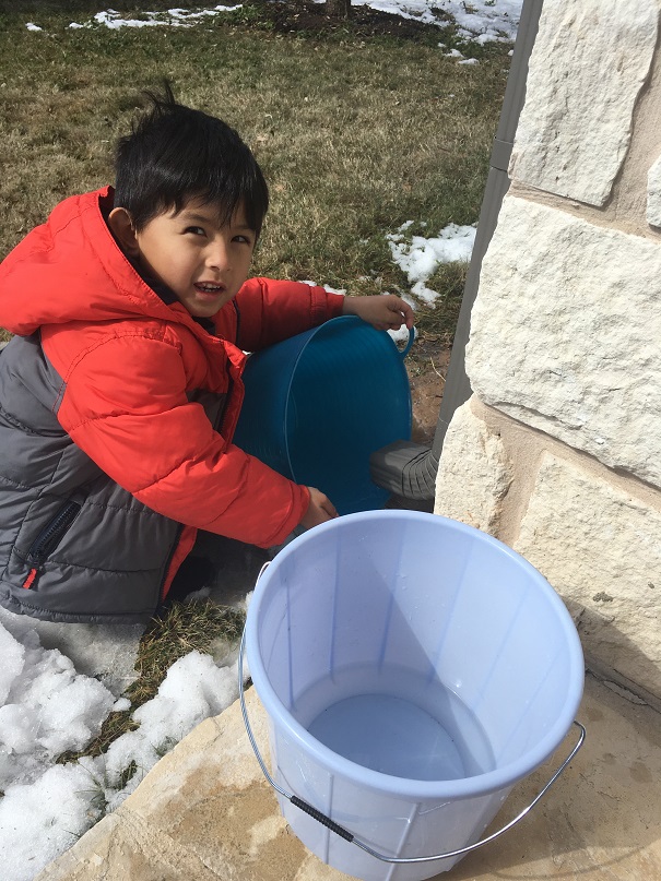 A boy collecting water from a gutter downspout in Texas